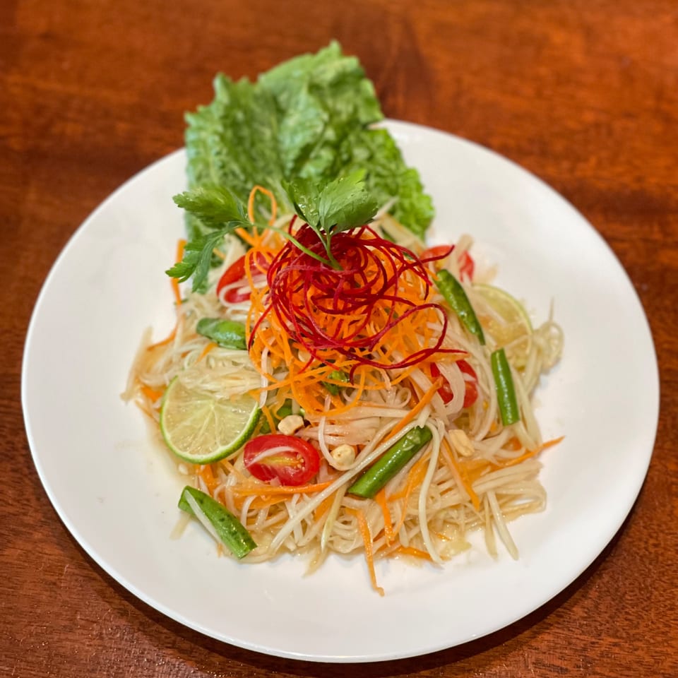 My Black Thai's Som Tum, a vibrant papaya salad with lime, tomatoes, and green beans.