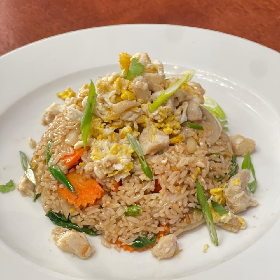 My Black Thai's chicken fried rice with carrots, scallions, and scrambled egg on a white plate.
