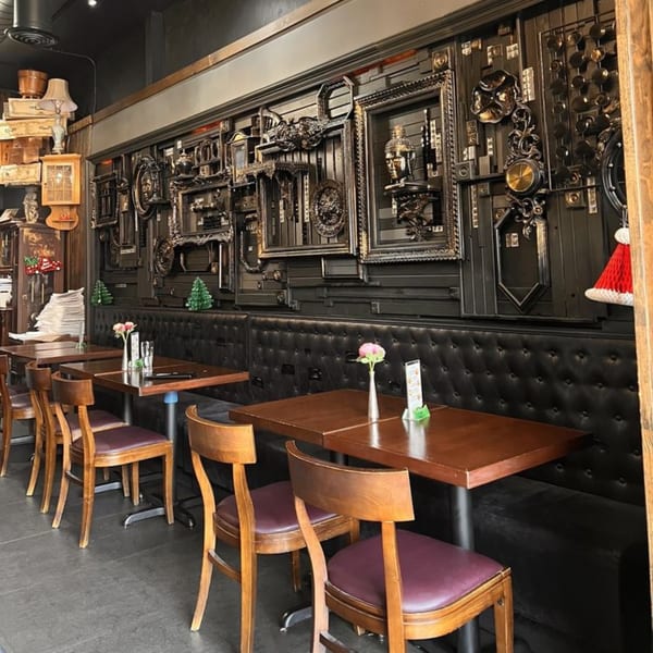 Interior of My Black Thai restaurant with dark, ornate wall decor, wooden tables, and black booth seating.