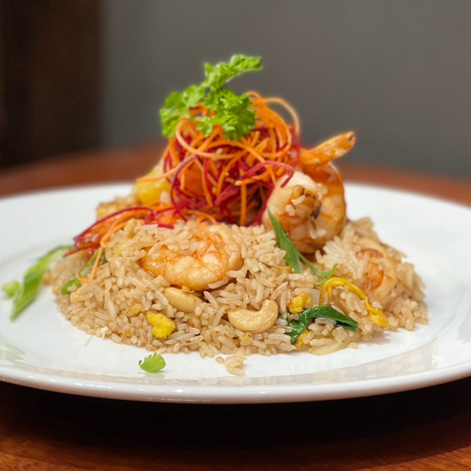My Black Thai's shrimp fried rice with cashews, egg, and shredded carrots on a white plate.